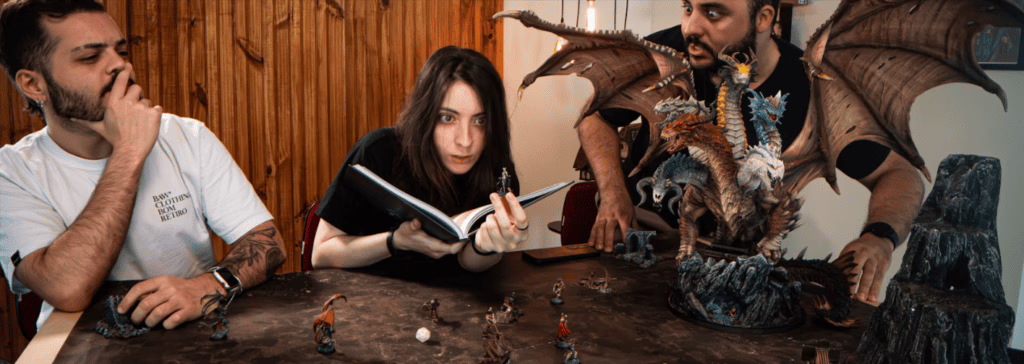 Three players in an RPG session with various Loot Studios miniatures and a dragon statue on the table