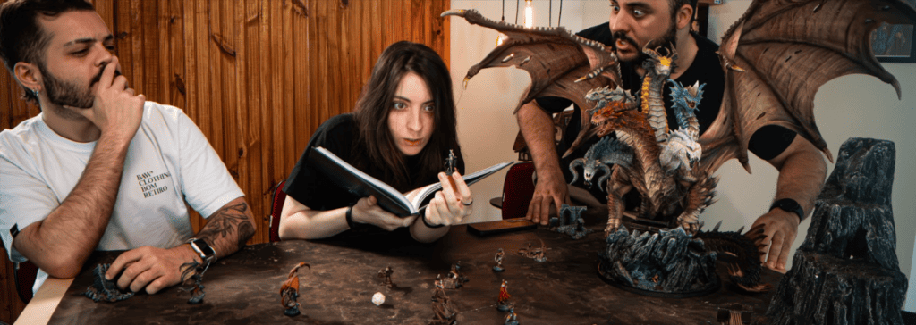Three players in an RPG session with various Loot Studios miniatures and a dragon statue on the table